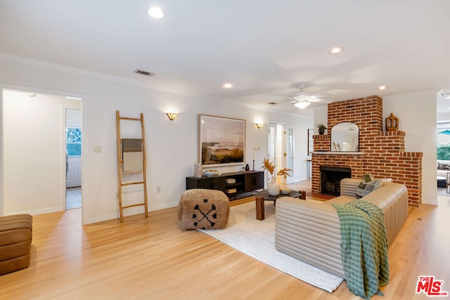 living room with wood-type flooring, a fireplace, ceiling fan, and ornamental molding