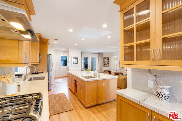 kitchen with sink, light hardwood / wood-style floors, exhaust hood, and stainless steel fridge