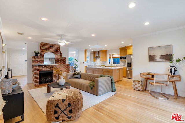 living room featuring crown molding, light hardwood / wood-style flooring, a brick fireplace, and ceiling fan