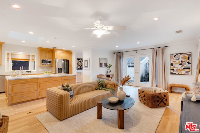 living room featuring light hardwood / wood-style floors, sink, crown molding, and french doors