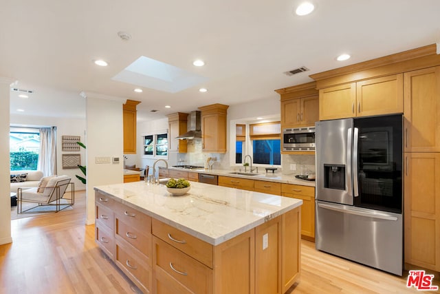 kitchen with sink, a kitchen island with sink, wall chimney range hood, and stainless steel appliances