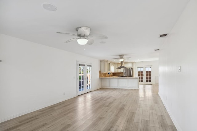 unfurnished living room with light hardwood / wood-style flooring, ceiling fan, and french doors