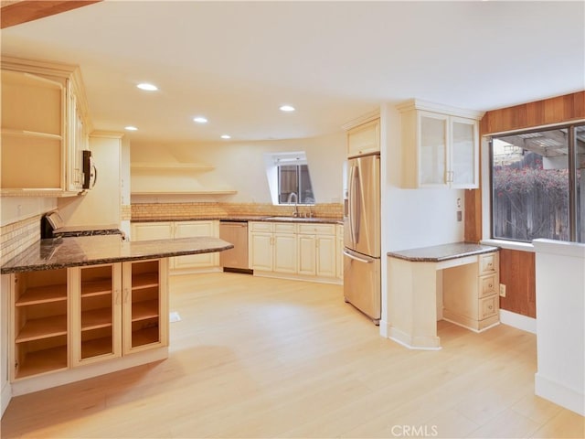 kitchen with dark stone counters, a kitchen breakfast bar, kitchen peninsula, a wealth of natural light, and stainless steel appliances