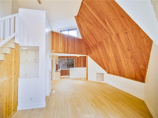 additional living space with vaulted ceiling, wooden walls, and light hardwood / wood-style flooring