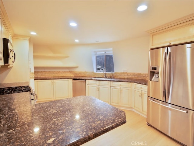 kitchen featuring sink, appliances with stainless steel finishes, kitchen peninsula, dark stone counters, and cream cabinets