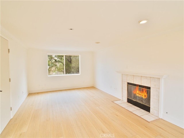 unfurnished living room featuring a tiled fireplace and light wood-type flooring