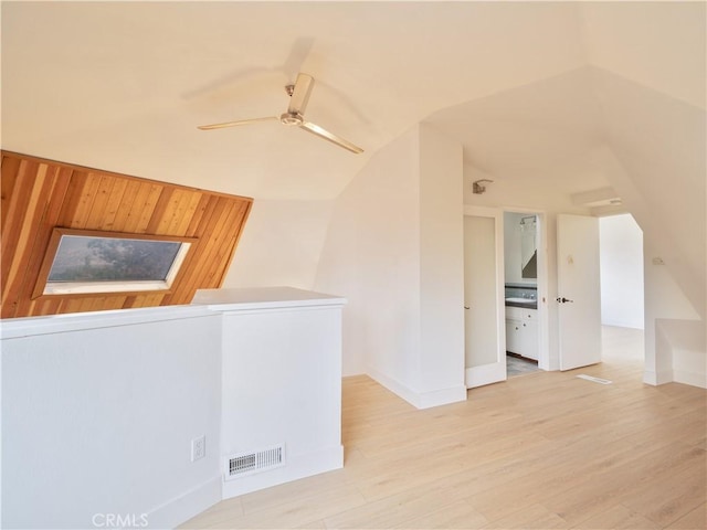 spare room with vaulted ceiling, ceiling fan, and light wood-type flooring