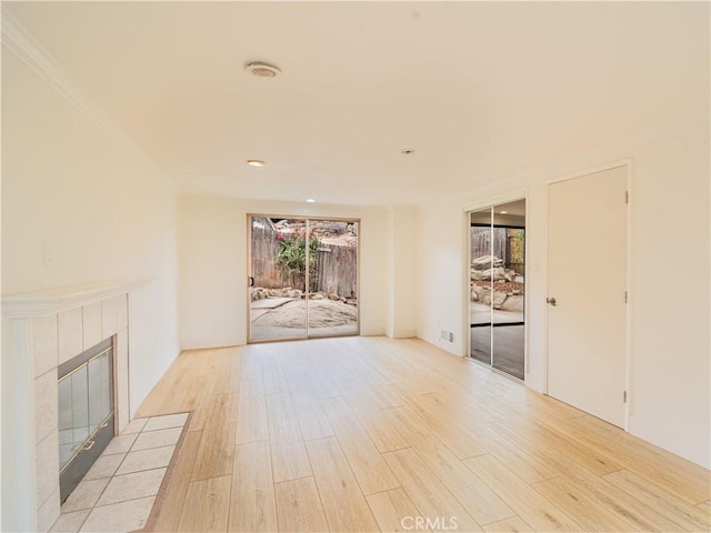 unfurnished living room with a tiled fireplace and light hardwood / wood-style flooring