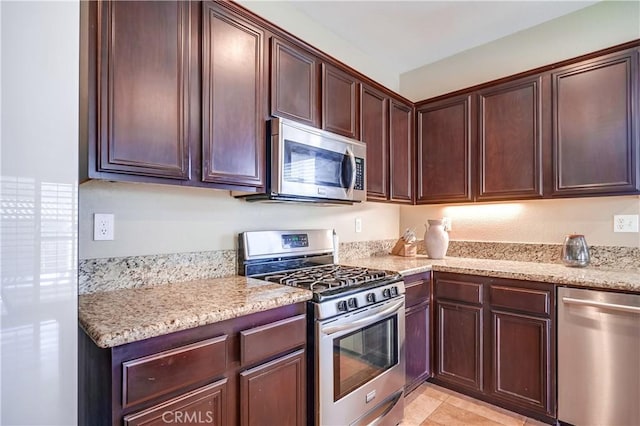 kitchen featuring light stone counters, dark brown cabinetry, and appliances with stainless steel finishes