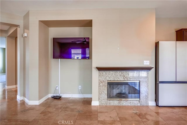 unfurnished living room featuring ceiling fan, light tile patterned floors, and a high end fireplace