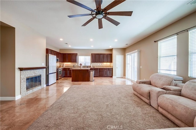 unfurnished living room with ceiling fan, a wealth of natural light, and light tile patterned floors