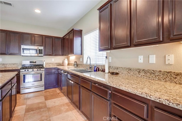 kitchen with sink, dark brown cabinetry, light stone countertops, and appliances with stainless steel finishes