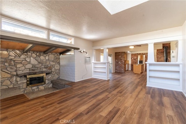 unfurnished living room with wood-type flooring, a wood stove, a wealth of natural light, and a textured ceiling