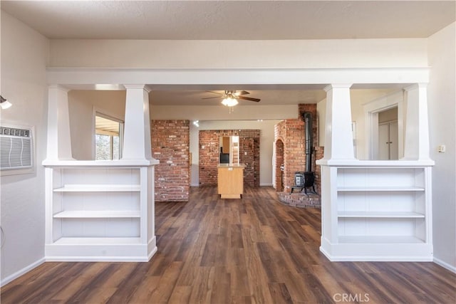 interior space featuring ceiling fan, a wood stove, a textured ceiling, and dark hardwood / wood-style floors