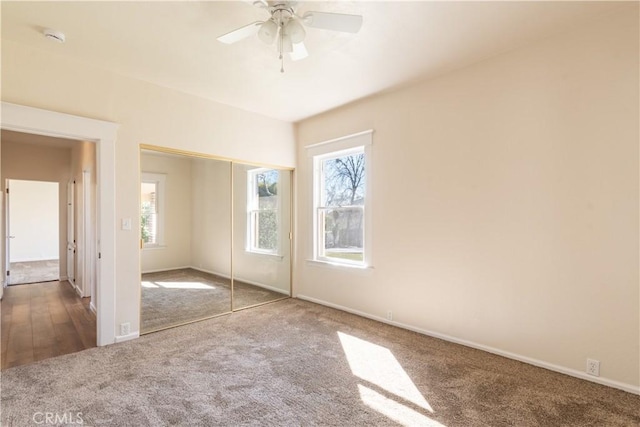 unfurnished bedroom with a closet, ceiling fan, and dark colored carpet