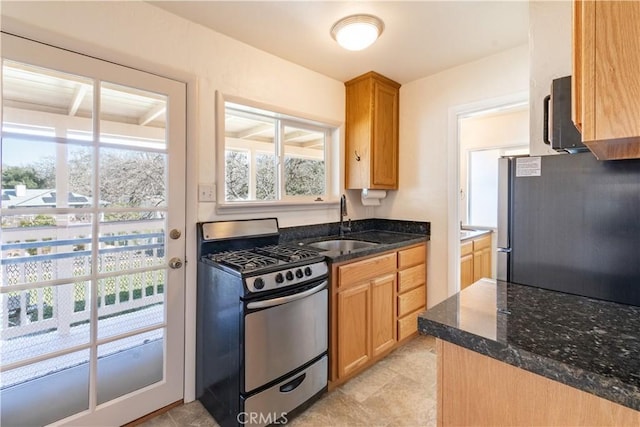 kitchen featuring sink, stainless steel appliances, and dark stone counters