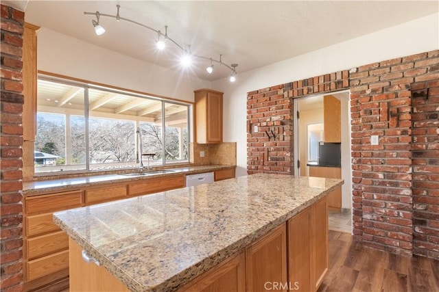 kitchen with white dishwasher, sink, a kitchen island, light stone counters, and dark hardwood / wood-style floors