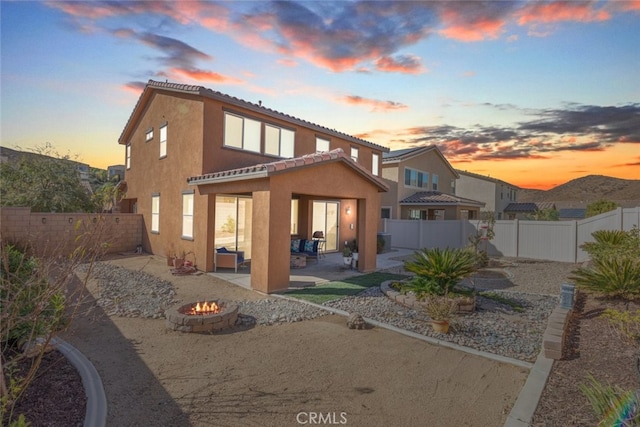 back house at dusk featuring a fire pit and a patio