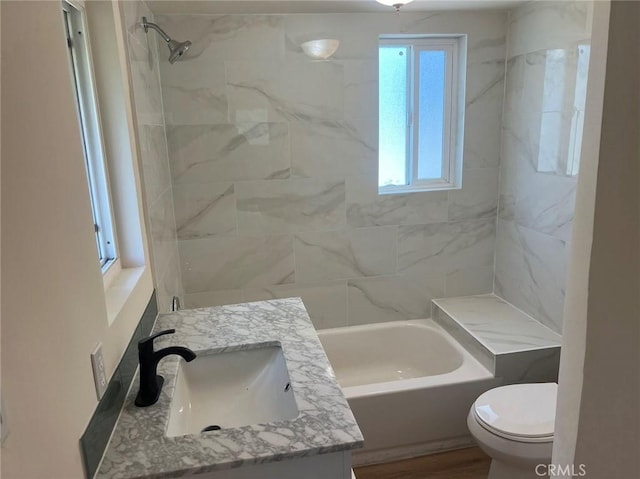 full bathroom with vanity, tiled shower / bath combo, and toilet