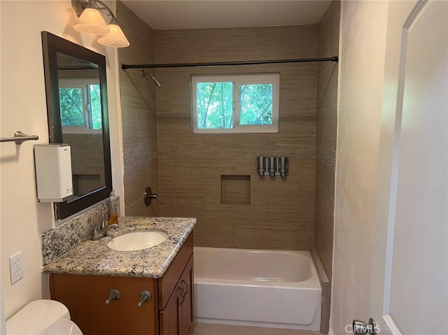 full bathroom featuring vanity, tiled shower / bath, and toilet