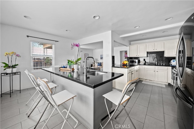 kitchen featuring stainless steel refrigerator, sink, a breakfast bar area, decorative backsplash, and kitchen peninsula