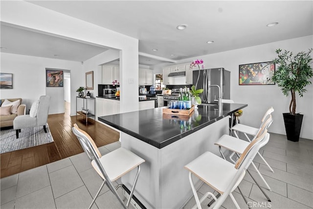 kitchen featuring a kitchen bar, sink, white cabinetry, kitchen peninsula, and stainless steel appliances