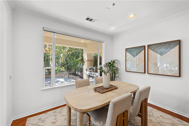 dining space with light hardwood / wood-style floors, ornamental molding, and plenty of natural light