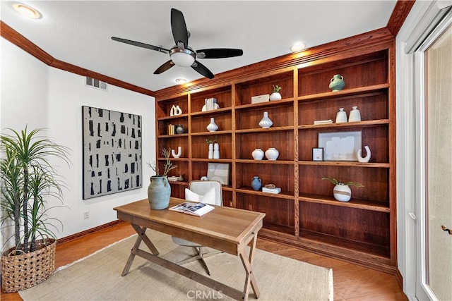 office area with light hardwood / wood-style floors, built in features, ornamental molding, and ceiling fan