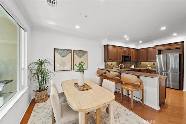 dining area featuring ornamental molding and light wood-type flooring