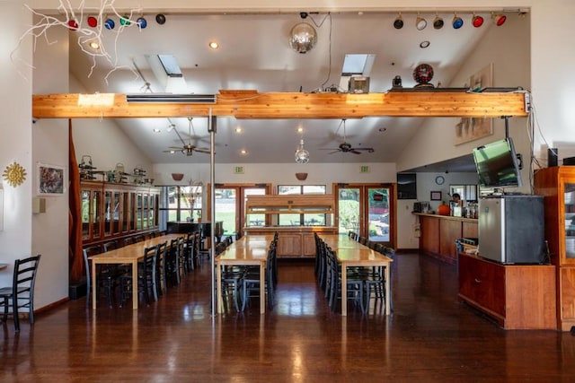 dining space featuring ceiling fan, dark hardwood / wood-style flooring, high vaulted ceiling, a skylight, and beamed ceiling