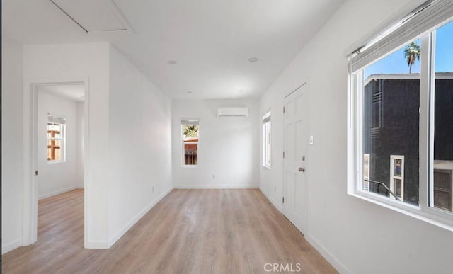 corridor with an AC wall unit and light hardwood / wood-style floors