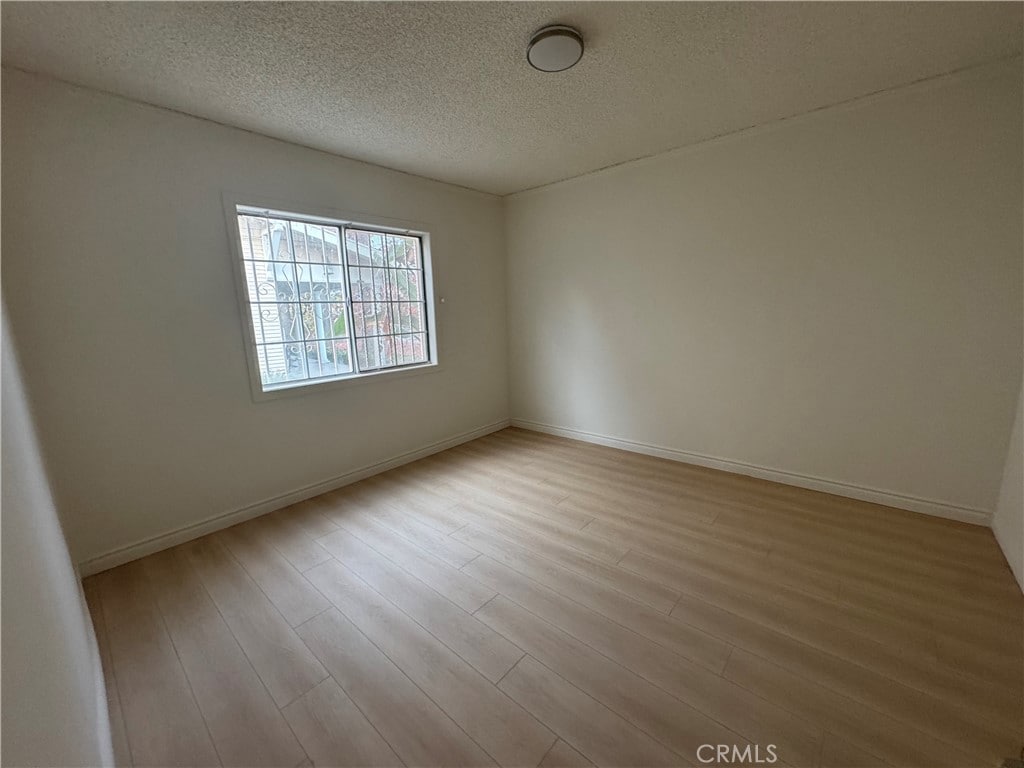 spare room featuring a textured ceiling and light hardwood / wood-style flooring