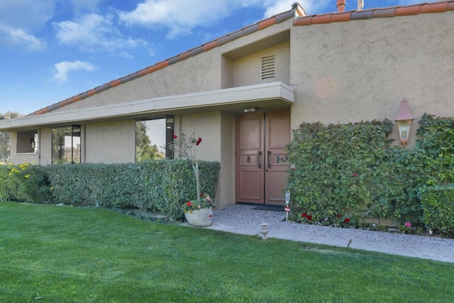 doorway to property with a lawn