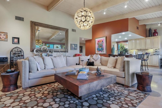 living room featuring beamed ceiling, a towering ceiling, a notable chandelier, and track lighting