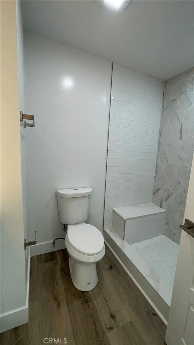 bathroom with hardwood / wood-style flooring, a shower, and toilet