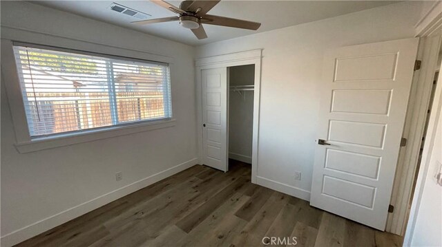 unfurnished bedroom featuring a closet, ceiling fan, dark hardwood / wood-style floors, and multiple windows