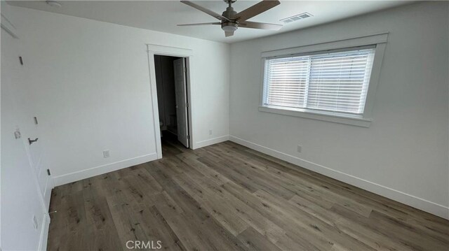 unfurnished bedroom with a spacious closet, ceiling fan, and dark hardwood / wood-style flooring