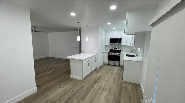 kitchen with kitchen peninsula, decorative light fixtures, sink, white cabinets, and stainless steel appliances