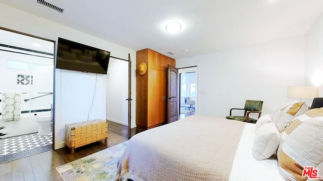 bedroom with connected bathroom and dark hardwood / wood-style flooring