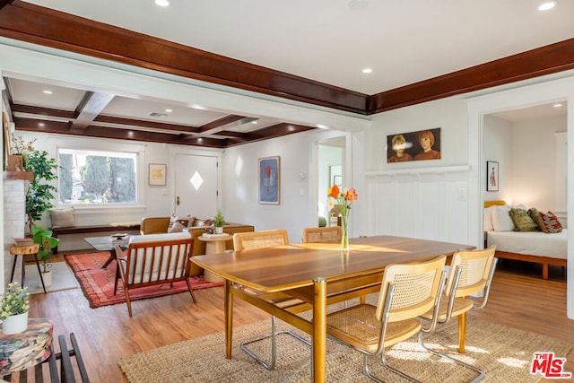 dining space featuring beam ceiling, coffered ceiling, and light hardwood / wood-style flooring