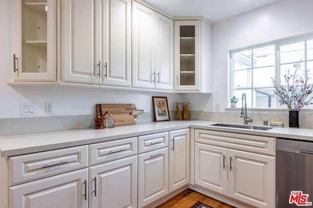 kitchen featuring sink, white cabinetry, light hardwood / wood-style flooring, and stainless steel dishwasher