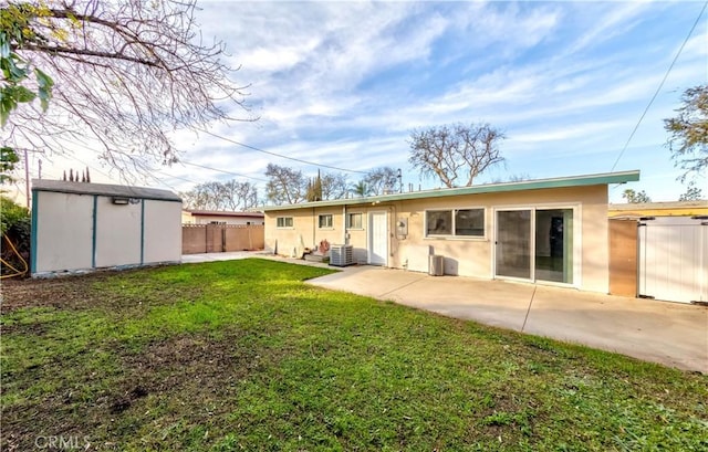 rear view of property with a patio area, cooling unit, a lawn, and a storage unit