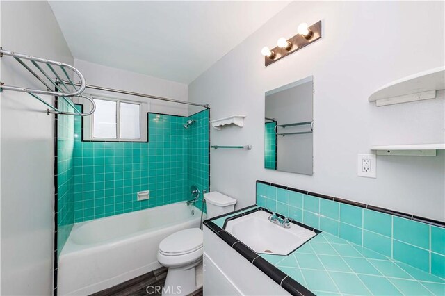 full bathroom featuring wood-type flooring, toilet, tiled shower / bath, and vanity