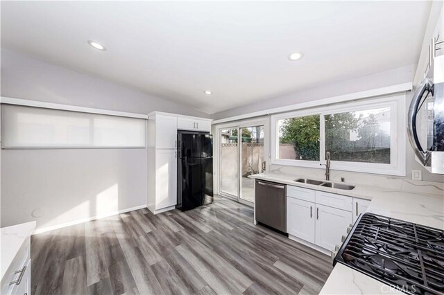 kitchen with light stone counters, white cabinetry, lofted ceiling, and appliances with stainless steel finishes