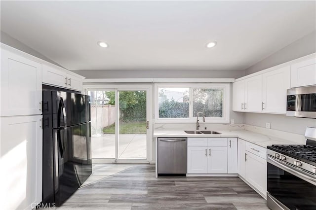 kitchen featuring light stone countertops, appliances with stainless steel finishes, white cabinetry, dark hardwood / wood-style flooring, and sink