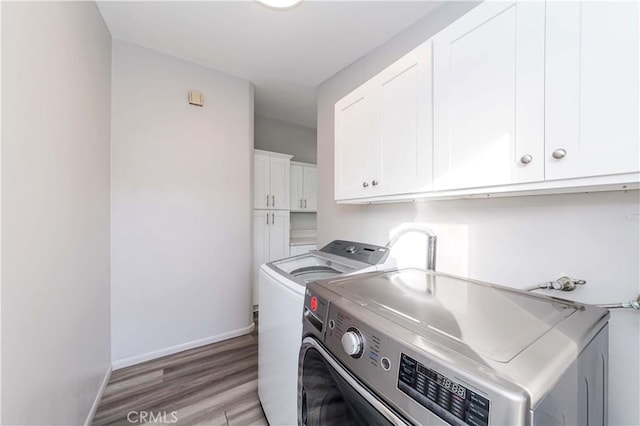 laundry area featuring separate washer and dryer, cabinets, and light hardwood / wood-style floors