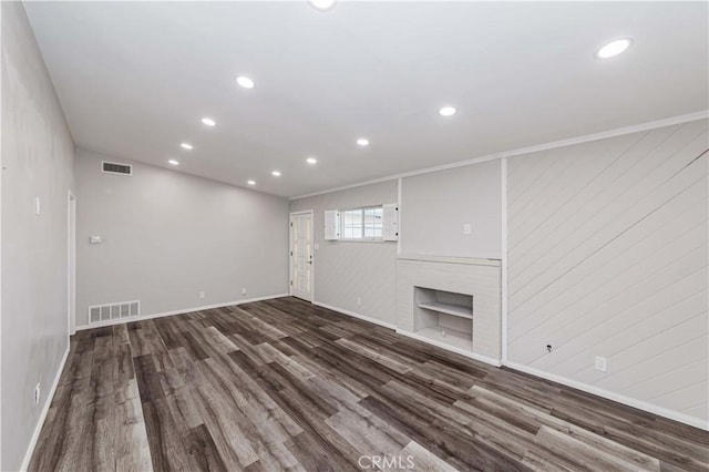 unfurnished living room featuring dark wood-type flooring, crown molding, and a fireplace