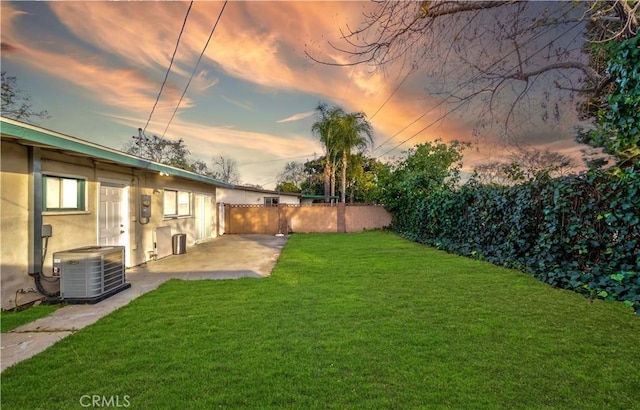 yard at dusk with a patio, cooling unit, and fence