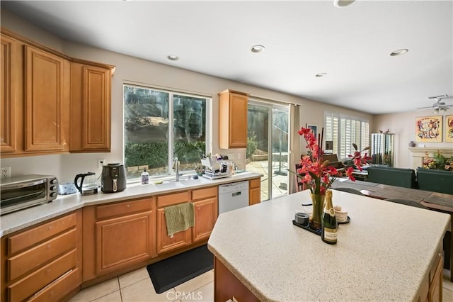 kitchen featuring sink, a center island, light tile patterned floors, white dishwasher, and ceiling fan