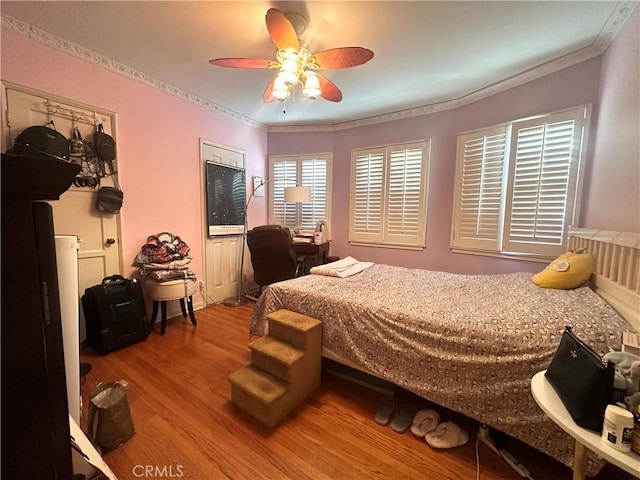 bedroom featuring hardwood / wood-style floors, ceiling fan, and ornamental molding